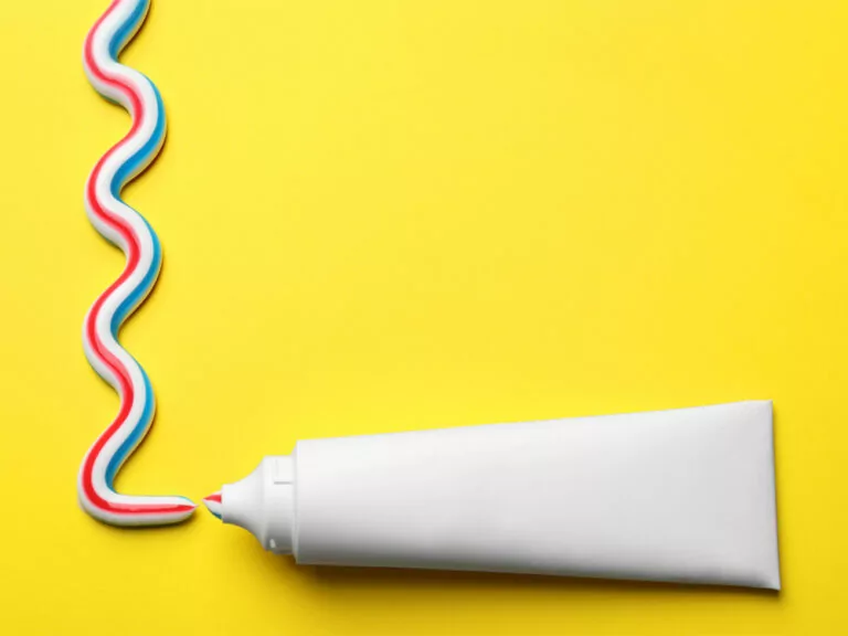 white tube of toothpaste on a yellow background