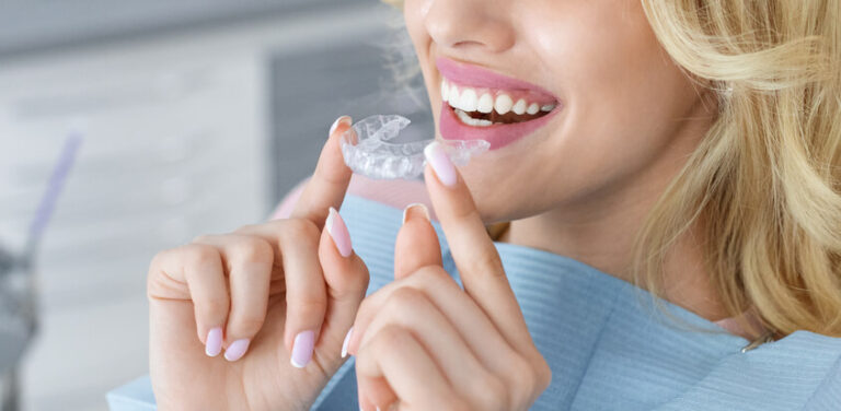 smiling woman holding an Invisalign® aligner