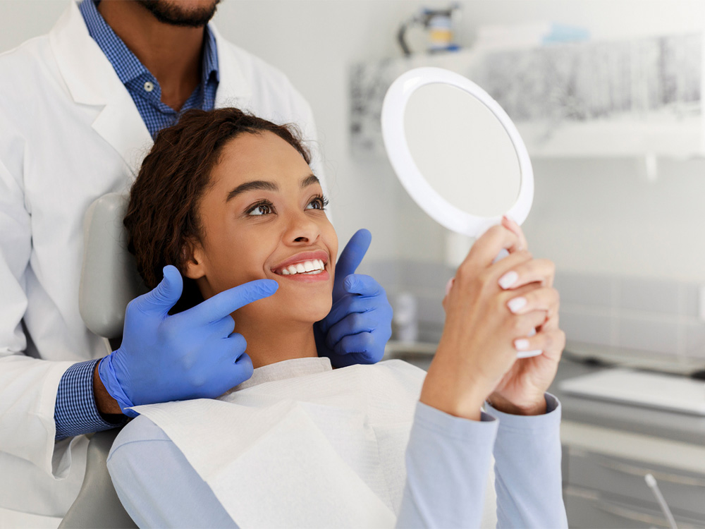 Patient smiling looking into mirror at dentist office
